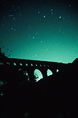 Deux étoiles filantes dans le ciel étoilé du Pont du Gard ; Le 18 novembre 1999 en fin de nuit, la Terre a traversé un nuage dense de poussières laissées par la comète Tempel-Tuttle. Il en a résulté une spectaculaire pluie d'étoiles filantes au dessus de l'Europe. Cette pluie correspond à l'essaim météoritique des Léonides. Sur cette image, prise sur le site du Pont du Gard, deux météores brillants et courts traversent le ciel. 