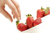 Woman taking a strawberry in studio