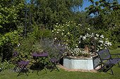 Well and furniture in a private garden in june Loiret France ; The garden of Chantal and Alain.<br>