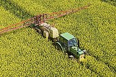 Air shot of a tractor in a field of Colza in flower ; This tractor pulverizes an insecticidal treatment (against charancon the siliques ones) or fungicide (against sclerotinia).