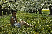 Woman sitting in an orchard of cherry trees in spring