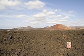 Cooled lava field on Lanzarote island Canary island ; Malpaïs area. There is a ban panel for walking on cooled lava flows.