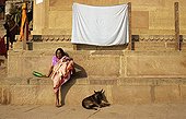 Woman and Dog sitting on ghats India ; Site: Benares town, Uttar Pradesh land<br>Edifice: Ghats, serie of steps leading down to a body of water in India