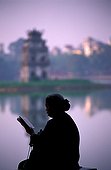 Old woman reading near water Hanoi Vietnam