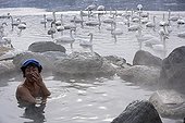 Man taking a bath in an onsen near a lake Japan  ; An onsen is a hot spring.