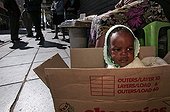 Street vendor with her baby in a box Johannesburg ; Cardboard box used as crib.