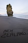 New Zealand written on sand at beach ea stack in background