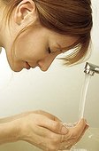 Young woman washing her face with water