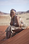 Elderly woman San wearing traditional dress sitting on sand ; In the private reserve named "N/a’an ku sê", welfare programs and health support converge to maintain populations of Bushmen in good health and to reintroduce the wild Cheetahs. This nomadic group of hunter-gatherers has a history dating back over 20,000 years. Their close relationship and perfect their knowledge of animals allowed to live and feed in the deserts of southern Africa.