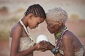 San woman offering an ostrich egg as a gift to young girl ; For the making of jewellery. <br>In the private reserve named "N/a’an ku sê", welfare programs and health support converge to maintain populations of Bushmen in good health and to reintroduce the wild Cheetahs. This nomadic group of hunter-gatherers has a history dating back over 20,000 years. Their close relationship and perfect their knowledge of animals allowed to live and feed in the deserts of southern Africa.