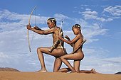 Male San hunter armed with bow and arrow Namibia ; Farther passing down traditional hunting techniques to his son.<br>In the private reserve named "N/a’an ku sê", welfare programs and health support converge to maintain populations of Bushmen in good health and to reintroduce the wild Cheetahs. This nomadic group of hunter-gatherers has a history dating back over 20,000 years. Their close relationship and perfect their knowledge of animals allowed to live and feed in the deserts of southern Africa.