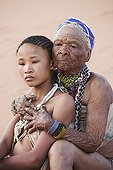 Young San girl with old woman embracing Namibie ; In the private reserve named "N/a’an ku sê", welfare programs and health support converge to maintain populations of Bushmen in good health and to reintroduce the wild Cheetahs. This nomadic group of hunter-gatherers has a history dating back over 20,000 years. Their close relationship and perfect their knowledge of animals allowed to live and feed in the deserts of southern Africa.