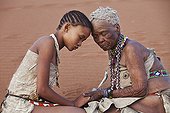 Young San girl with old woman embracing Namibie ; In the private reserve named "N/a’an ku sê", welfare programs and health support converge to maintain populations of Bushmen in good health and to reintroduce the wild Cheetahs. This nomadic group of hunter-gatherers has a history dating back over 20,000 years. Their close relationship and perfect their knowledge of animals allowed to live and feed in the deserts of southern Africa.
