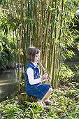 Little girl playing a flute carved from a reed and Bamboo  ; Girl aged 5 years