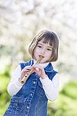 Little girl playing a flute carved from a reed ; Girl aged 5 years 