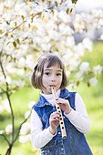Little girl playing a flute carved from a reed ; Girl aged 5 years 