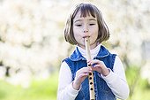 Little girl playing a flute carved from a reed ; Girl aged 5 years