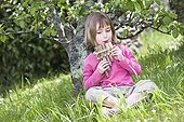 Girl playing a pan flute carved from a reed  ; Girl aged 5 years 
