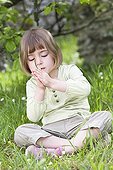 Girl blowing a whistle made from a blade of grass  ; Girl aged 5 years 