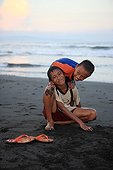 Boys playing on a black sand beach Bali Indonesia