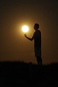 Person giving the impression of playing basket with the Moon ; A basketball player spins the Full Moon at the end of his finger