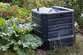 Plastic compost container in an organic garden
