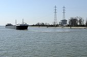 Barge on canal & Fessenheim Nuclear Power Plant France ; Overlooking the Grand Canal of Alsace on the Rhine channeled. Commissioned in 1977, it's the oldest operational nuclear power plant in France.