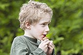 Boy whistling with a walnut shell ; 7 years old boy
