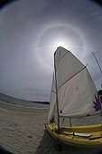 Sailboat in front of the Sun and its halo of 22 ° radius 