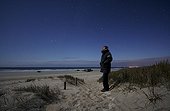 Man on a dune watching the sky lit by the moon France