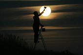 Woman giving the impression of painting the Moon France ; During a partial lunar eclipse, a woman pretends to paint part of the Moon diving into the Earth's shadow.