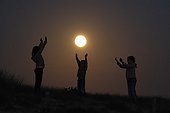 Children giving the impression of playing ball with the Moon