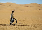 Child playing with a wheel in the sand dunes of Morocco