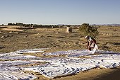 Woman stretching the sheets on the dunes at Merzouga Morocco