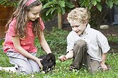 Children and a hen 'Negre-Soie' in a garden France ; Girl 10 year old<br>Boy 7 year old