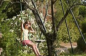 Little girl playing on a swing in a garden