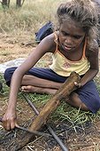Aboriginal girl cooking a kangaroo tail in Australia ; Warlpiri Aborginal community of Alice Spring