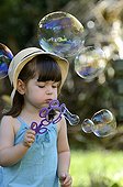 Girl making soap bubbles in a garden France  ; Age: 3 years