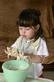 Girl preparing cake batter France ; Age: 3 years