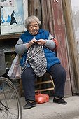 Woman knitting in a street of old Shanghai in China