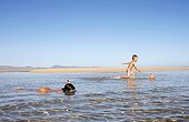 Boy, 4 years, trying to catch fish with a net, girl, 8 years, making first attempts at snorkeling in shallow water, on the beach of Fuerteventura, Canary Island, Spain, Europe