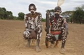 Two Karo warriors with body paintings and a rifle seated on their headrest, Omo river valley, Southern Ethiopia, Africa