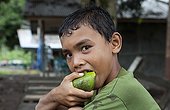 Boy eating a mango in Indonesia