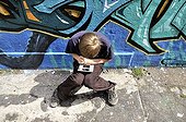 Ten-year-old boy playing with his Nintendo in front of a graffiti wall, Germany, Europe