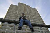 Boy, 9, playing with his Nintendo in front of a high-rise apartment building, satellite town of Chorweiler in Cologne, North Rhine-Westphalia, Germany, Europe