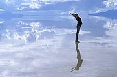Young woman reflecting on the surface of the flooded salt desert Salar de Uyuni, Bolivia
