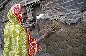 Woman pressing cow dung to dry on the wall of a house, Shibpur district, Howrah, Kolkata, West Bengal, India, Asia