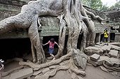 Tourists visiting the temple of Ta Prohm at Angkor Cambodia ; The walls are trapped in the roots of giant cheese. 