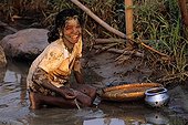Girl Washing small fry near a rice field India