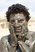 Tourist smearing mud on the banks of the Dead Sea Jordan
